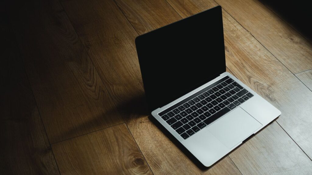 MacBooks aus dem Refurbishment für Bildbearbeitung und Homeoffice Aufgeklapptes MacBook auf einem Holzboden im Seitenlicht
