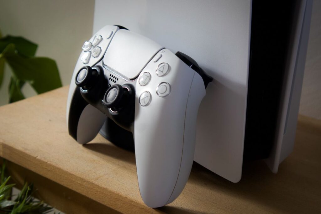 Games console with its controller resting against it on a shelf