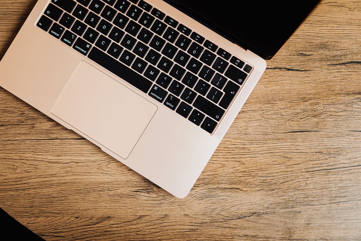 Hände tippen auf der Tastatur eines silbernen Laptops